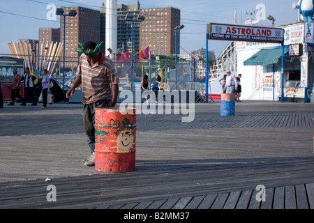 Un uomo che indossa una statua della libertà hat cerca per bottiglie e lattine nel cestino a Coney Island, Brooklyn, NY Foto Stock