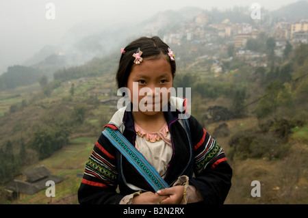 Un giovane nero tribale Hmong ragazza con il Misty Hills nei dintorni di Sapa Vietnam dietro di lei Foto Stock