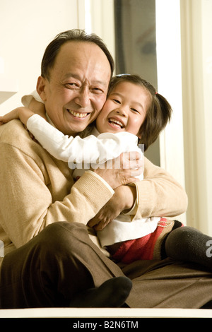 Ritratto di un uomo anziano che abbraccia il suo nipote e sorridente, Shanghai, Cina Foto Stock