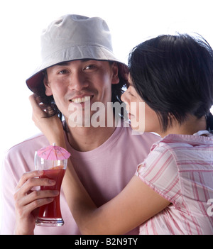 Ritratto di un giovane uomo con in mano un bicchiere di bicchiere da cocktail con una giovane donna seduta con bracci intorno Foto Stock
