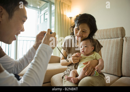 Close-up di una metà uomo adulto di scattare una foto di sua moglie e sua figlia Foto Stock