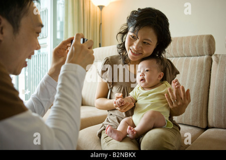 Close-up di una metà uomo adulto di scattare una foto di sua moglie e sua figlia Foto Stock