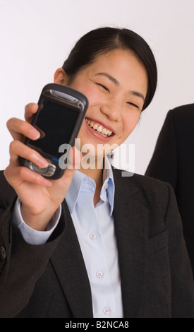 Ritratto di una imprenditrice che mostra un telefono cellulare e sorridente Foto Stock
