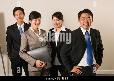 Ritratto di due imprenditori con due imprenditrici in piedi insieme in un ufficio Foto Stock