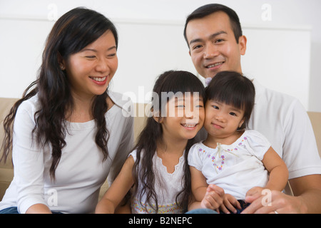 Close-up di una metà adulto giovane seduto con le loro due figlie su un lettino, Singapore Foto Stock