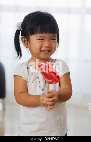 Close-up di una ragazza con un lecca-lecca e sorridente, Singapore Foto Stock
