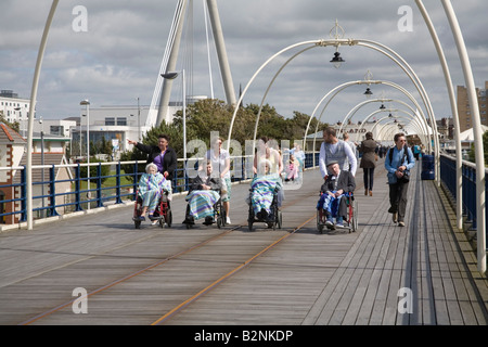 Southport Merseyside England UK Luglio cinque persone anziane disabili essendo spinto in carrozzina da loro caregivers lungo il molo Foto Stock