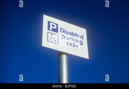 Il bianco e il cartello blu sul polo di argento con il profondo blu del cielo e simbolo della persona in carrozzina dichiarando P parcheggio disabili solo Foto Stock