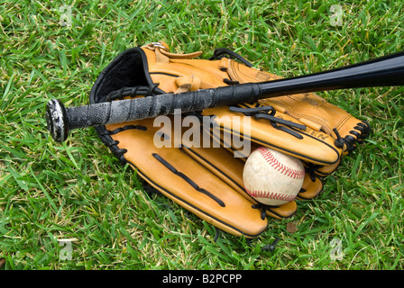 Un Guanto baseball palla e bat giacciono in erba prima di un gioco Foto Stock