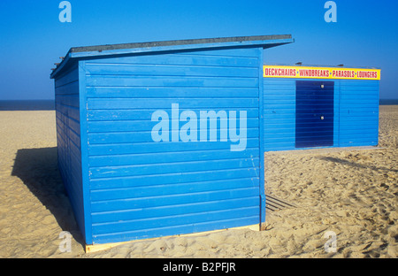 Due grandi dipinti blu beach capanne sulla soffice sabbia chiara nella luce della sera con segno sdraio frangiventi Ombrelloni Sdraio Foto Stock