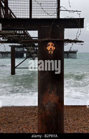 Il volto di Gesù Cristo viene spruzzato su un arrugginito colonna di supporto dei resti del vecchio molo di Brighton nel West Sussex. Foto Stock