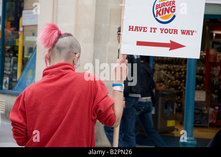 Cartello lavoratore con eleganti tinte rosso-capelli detiene un Burger King segno, Union Street, Bath Somerset, Regno Unito Foto Stock