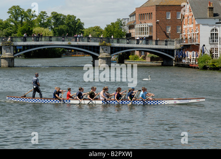 Dragon Boat e equipaggio sul Fiume Tamigi con il Windsor Eton ponte pedonale dietro, Windsor, Berkshire, Inghilterra Foto Stock