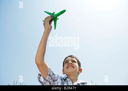 Ragazzo holding toy piano aloft Foto Stock