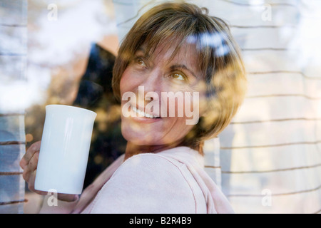 Donna che guarda fuori da una finestra Foto Stock