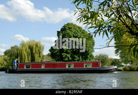 Narrowboat rosso con due uomini a poppa, Fiume Tamigi, Egham Surrey, Inghilterra, Gran Bretagna, Regno Unito, Europa Foto Stock