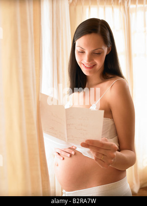 Donna incinta la lettura di una lettera Foto Stock