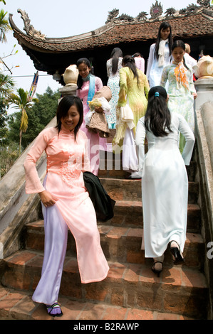 Una folla di ragazze vietnamita in seta tradizionale ao dai tunica salendo la scalinata della pagoda su un pilastro ad Hanoi Vietnam Foto Stock