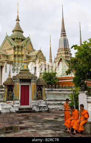 I monaci buddisti accanto ad alcuni stupa di Wat Pho tempio di Bangkok, Tailandia Foto Stock