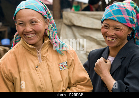 Due vecchi Hmong di fiori per le donne di portare la testa tradizionali sciarpe di ridere in un mercato in Vietnam Foto Stock