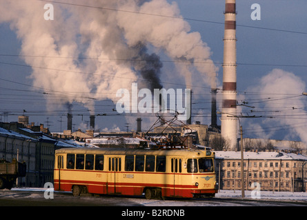 Il tram la guida passato pennacchi di fumo di una fabbrica Foto Stock