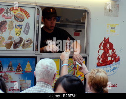 Ice Cream amanti godono di un cono di gelato morbido a partire da un Mr Softee carrello su Wall Street a New York Foto Stock