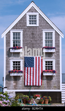 La Nuova Inghilterra incastrata Cape Cod house battenti bandiera americana per il quarto di luglio. Foto Stock