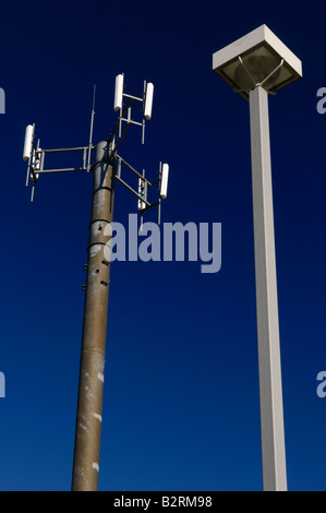 Comunicazioni tramite telefono cellulare la torre contro un cielo blu con una lampada posta Foto Stock