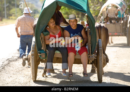 Due donne ride in un bue carrello guida lungo la strada in Guanacaste. Il bue sono tradizionali trasporti in Costa Rica e Guanacaste. Foto Stock