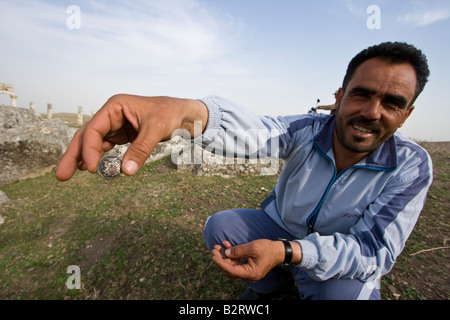 Uomo di vendita falsi antiche monete romane presso il Runis romano di Apamea in Siria Foto Stock