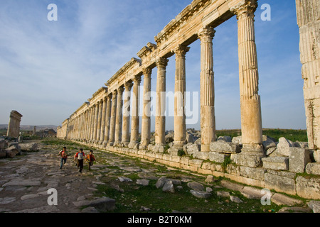 Ragazzi locali e la Collonade presso le rovine Romane di Apamea in Siria Foto Stock