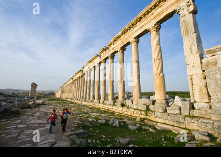 Ragazzi locali e la Collonade presso le rovine Romane di Apamea in Siria Foto Stock