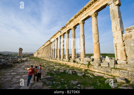 Ragazzi locali e la Collonade presso le rovine Romane di Apamea in Siria Foto Stock