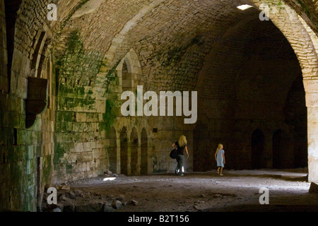 I turisti all'interno di una grande camera con soffitto a volta in Krak des Chevalier Castello dei Crociati in Siria Foto Stock