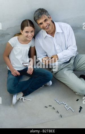 Padre e figlia gioca domino, sorridente in telecamera, ad alto angolo di visione Foto Stock