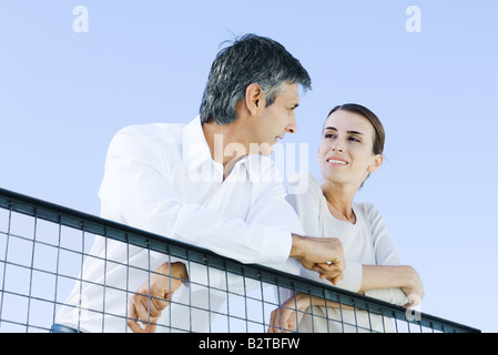 Giovane appoggiata sul filo di recinzione, sorridente ad ogni altro a basso angolo di visione Foto Stock