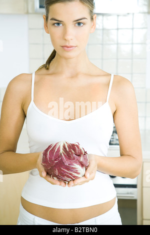 Giovane donna tenendo una testa di radicchio lattuga in cucina Foto Stock