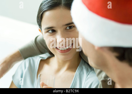 Giovane donna sorridente a uomo in Santa hat, close-up Foto Stock