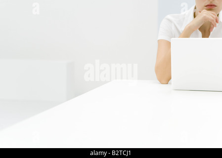 Donna che utilizza il computer portatile, la mano sotto il mento, vista ritagliata Foto Stock