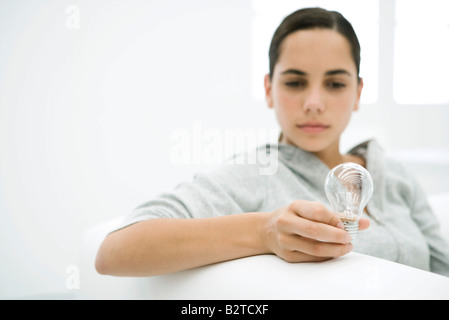 Teen ragazza guardando il bulbo di luce messa a fuoco su oggetti in primo piano Foto Stock