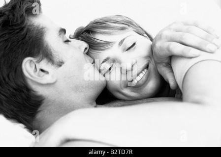 Giovane abbracciando, uomo baciando la donna di fronte, occhi di donna chiuso Foto Stock