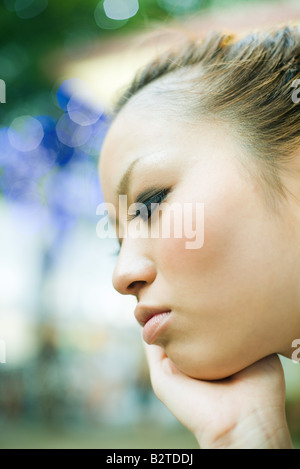 Giovane donna con la mano sotto il mento, profilo Foto Stock