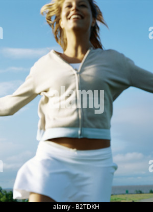 Donna in corsa all'aperto nel mantello e la felpa con cappuccio, close-up, sorridente Foto Stock