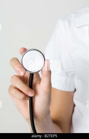 Nurse holding stetoscopio, vista ritagliata della mano Foto Stock