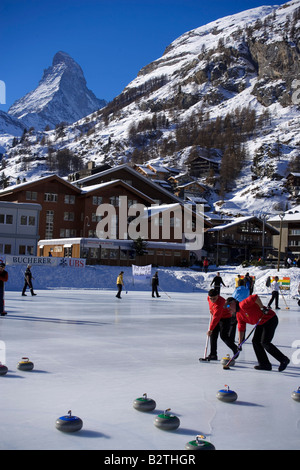 Persone curling su ghiaccio, Matterhorn sullo sfondo, Zermatt, Vallese, Svizzera (Curling: un rink gioco dove round pietre sono pr Foto Stock