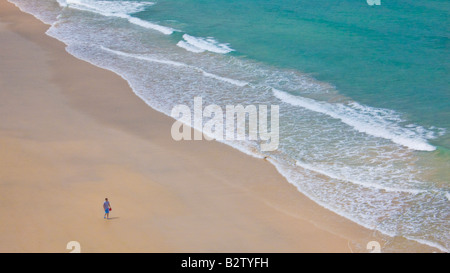 Tourist camminando sulla spiaggia vuota a Carbis Bay tra Hayle e St Ives Cornwall Inghilterra UK GB EU Europe Foto Stock