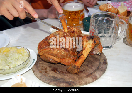 Lo scavo in una carne di maiale alla griglia con rafano e senape in Schweizerhaus beer garden Foto Stock