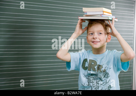 Ragazzo con libri sulla sua testa Foto Stock