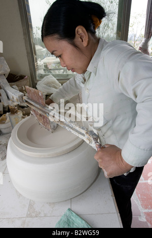 Giovane donna rivestimenti di argilla in eccesso dalla coppa Bat Trang in ceramica villaggio nei pressi di Hanoi Vietnam Foto Stock