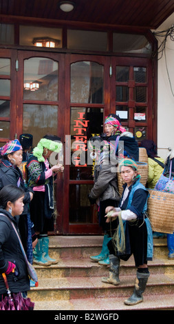 Nero hilltribe Hmong donne folla outswide Sapa alberghi spera di vendere ninnoli e mestieri Vietnam Foto Stock